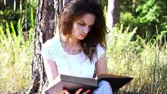 美丽的年轻女孩正在户外看书视频的预览图