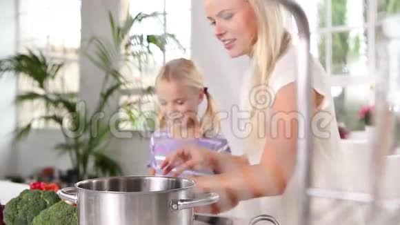 妈妈和女儿在锅里放蔬菜视频的预览图