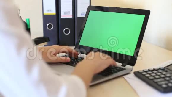一个女人用一个绿色键屏在笔记本电脑上打字的肩膀上视频的预览图