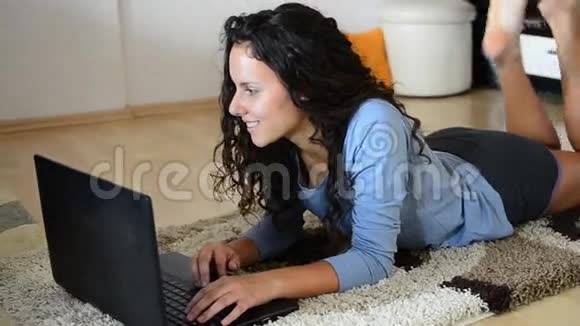 漂亮的少女用笔记本电脑躺在地板上视频的预览图