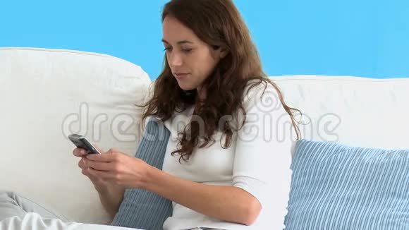 西班牙裔妇女在沙发上用手机写短信的肖像视频的预览图