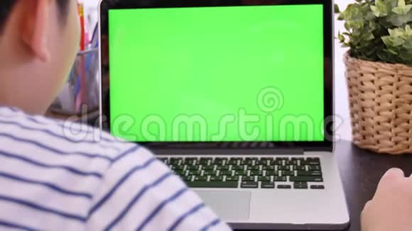 拍过肩膀的亚洲男孩看着绿色的屏幕办公室人员使用带有笔记本电脑绿色屏幕的笔记本电脑视频的预览图