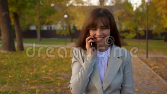 手机穿过秋天的公园微笑着视频的预览图