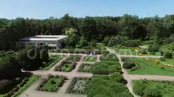 四架直升机拍摄美丽的绿色夏季花园与喷泉在中心人们挥动双手阳光明媚视频的预览图
