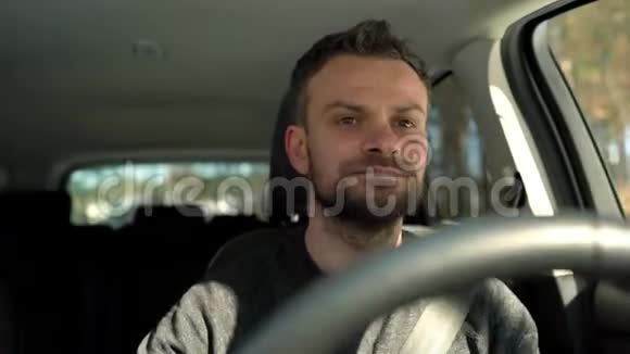 在晴朗的天气里一个满脸胡须的人开着一辆汽车在街上行驶视频的预览图