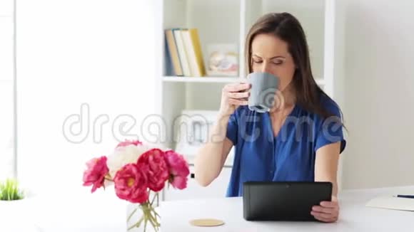 有平板电脑和咖啡的女人在家里或办公室视频的预览图