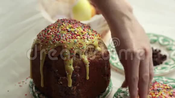 复活节蛋糕上有黄色的糖霜和五颜六色的花洒在白色的桌子上女孩甜蜜的谷物洒复活节蛋糕视频的预览图