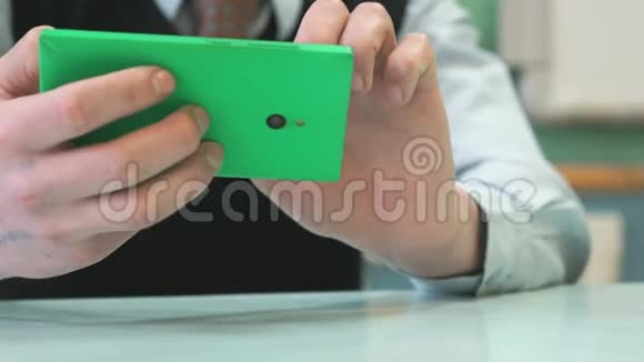 不知名的小学生拿着绿色智能手机视频的预览图