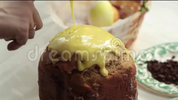 复活节蛋糕上有黄色的糖霜和五颜六色的花洒在白色的桌子上给女孩浇糖蛋糕视频的预览图
