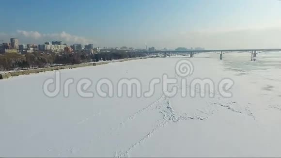 冬天飞过冰冻的河流河上的桥路基视频的预览图