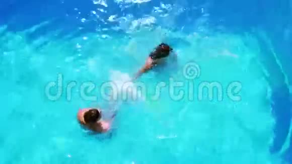 快乐的一对情侣在清澈的蓝色游泳池里嬉戏视频的预览图