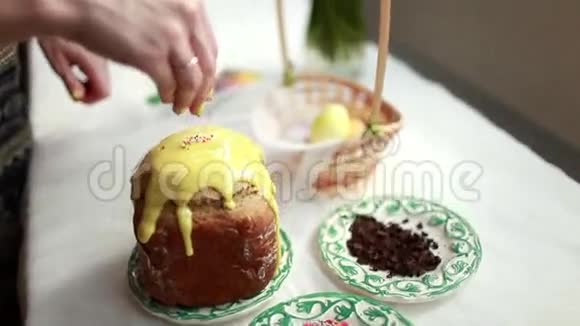 复活节蛋糕上有黄色的糖霜和五颜六色的花洒在白色的桌子上女孩甜蜜的谷物洒复活节蛋糕视频的预览图