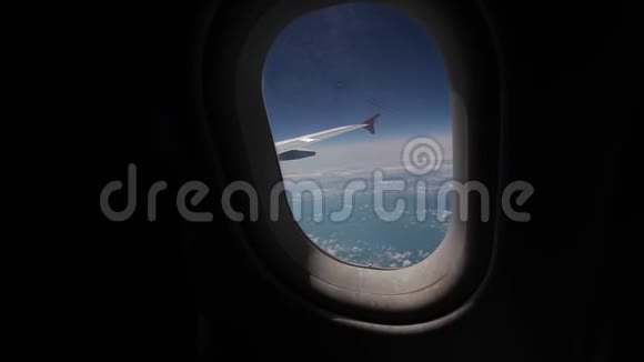 透过飞机的窗户观看蓝天和云彩带飞机机翼的飞机窗旅行视频的预览图