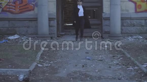 一个穿着黑色衣服和帽子的漂亮女孩沿着一座倒塌的旧建筑走着戴帽子的女孩视频的预览图