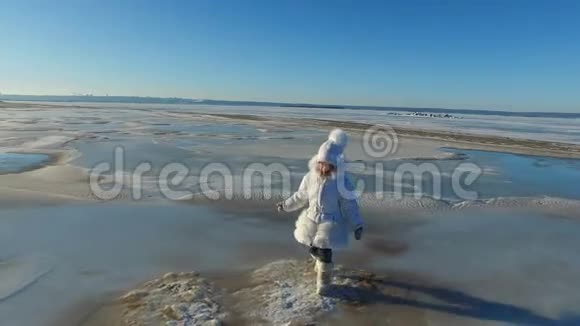 女孩走在冰上的大湖上女孩很高兴湖面结冰了孩子现在可以在冰上滑行了阳光明媚视频的预览图