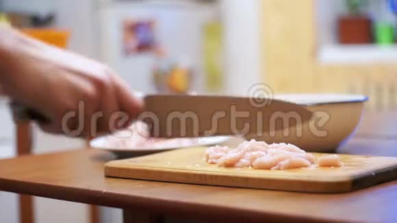 女人的手与刀切肉在木制的切割板在家庭厨房慢动作视频的预览图