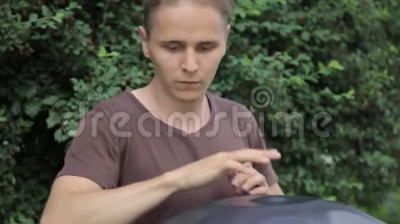 鼓手在行动坐在草地上玩手盘或挂鼓的家伙视频的预览图