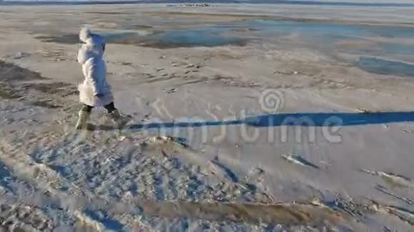 女孩走在冰上的大湖上女孩很高兴湖面结冰了孩子现在可以在冰上滑行了阳光明媚视频的预览图