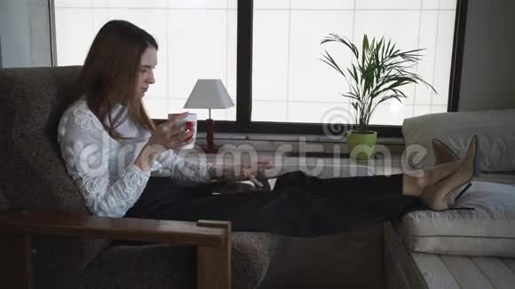 坐着喝咖啡的女人正在看她的装置视频的预览图