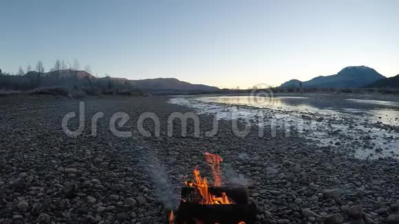 深秋早晨用高山在冰冻的河岸边温暖白桦火视频的预览图