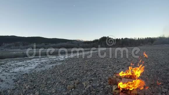 深秋早晨用高山在冰冻的河岸边温暖白桦火视频的预览图