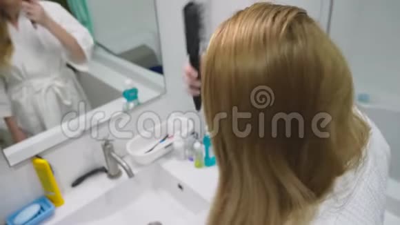 发健康脱发理念女人在浴室里梳着她那金发受损的干头发视频的预览图