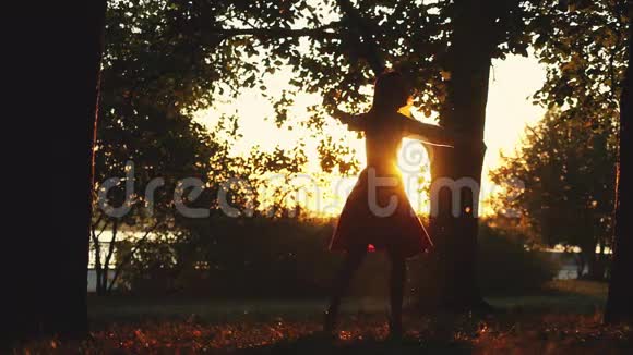 快乐的女孩在秋天的公园里在日落的时候在阳光的背景下缓慢地旋转着1920x1080视频的预览图