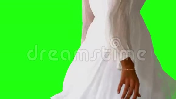 穿着白色连衣裙的女孩在绿色的屏幕上旋转闭上眼睛视频的预览图