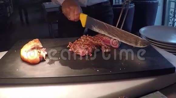 专业的贝夫牛排肉切服务与特殊设备和妇女的手在黑色厨房板视频的预览图