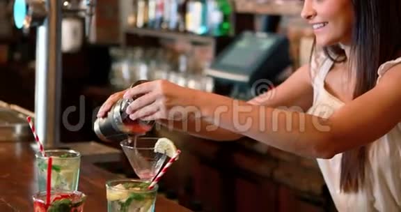 酒吧柜台上的酒吧服务员倒杯鸡尾酒视频的预览图