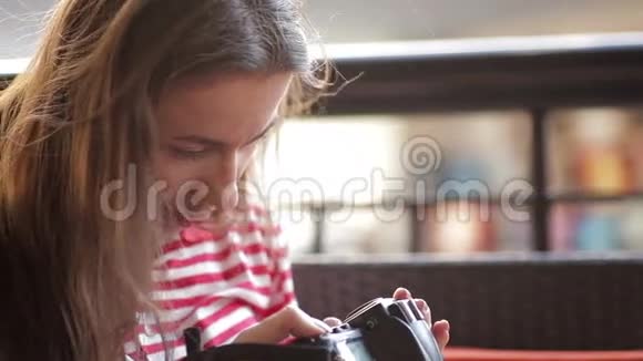 美丽的女孩坐在沙发上看着摄像机里的照片视频的预览图