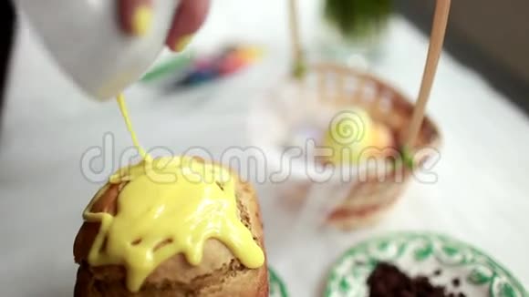 复活节蛋糕上有黄色的糖霜和五颜六色的花洒在白色的桌子上给女孩浇糖蛋糕视频的预览图