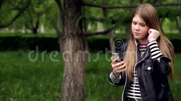 公园里戴着耳机听音乐的漂亮女孩视频的预览图