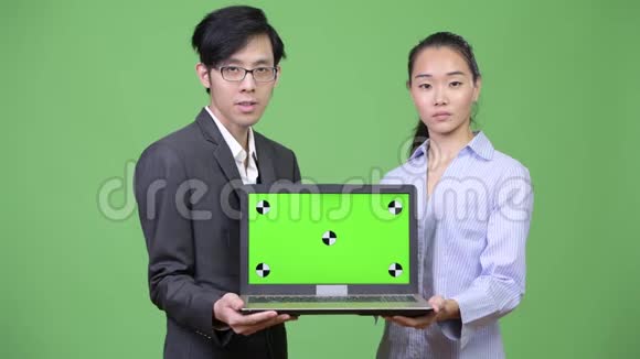 年轻的亚洲商业情侣一起展示笔记本电脑视频的预览图