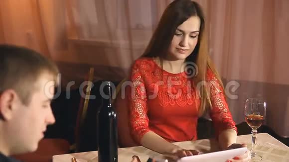 男人和女孩带着智能手机和两块平板电脑在咖啡馆度过浪漫的情人节视频的预览图