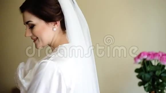 年轻可爱的幸福新娘抚摸着她的婚纱对着镜头微笑视频的预览图