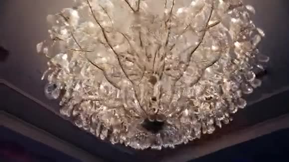 漂亮的复古豪华水晶支柱吊灯隔离在餐厅的白色墙壁上视频的预览图