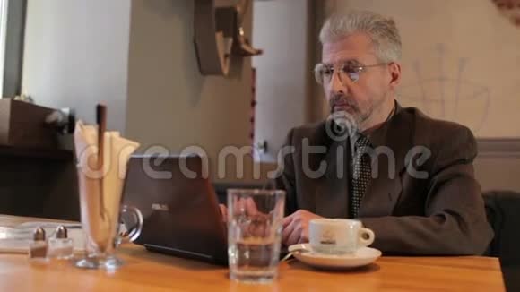 成年商人在咖啡馆的笔记本电脑上打字视频的预览图