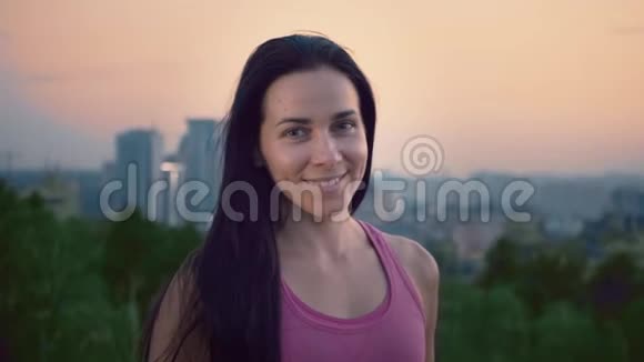 城市背景上一位迷人的女运动员的肖像一位身材健美的可爱年轻女子正在看视频的预览图