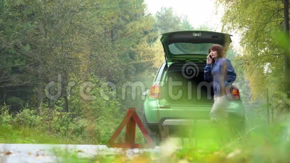 这名妇女用破车紧急呼叫恢复服务乡村公路警告三角视频的预览图