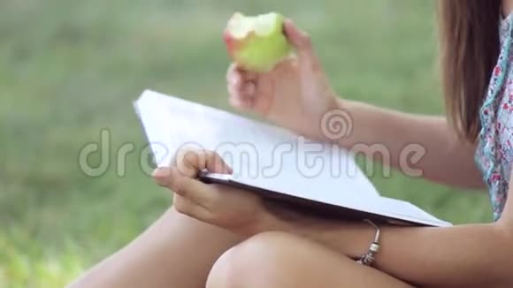 年轻女子在公园看书和吃苹果视频的预览图