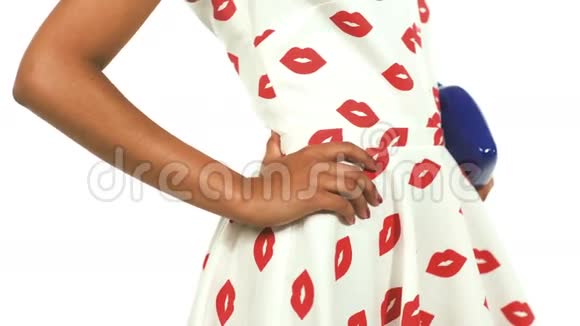 模特拿蓝色手袋在嘴唇形状在白色背景的工作室里穿着一件衬裙的模特视频的预览图