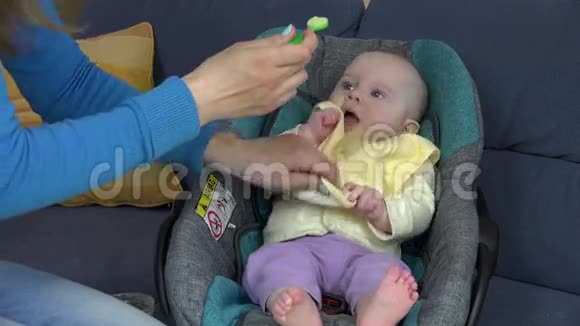 带黄色围兜的宝宝吃蔬菜坐在车座上视频的预览图