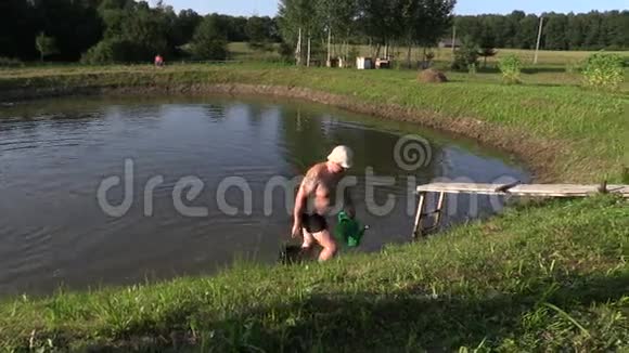 人用水桶从池塘里舀水插入手推车视频的预览图