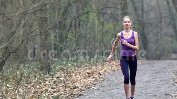 女跑步者正在公园的森林小径上慢跑视频的预览图