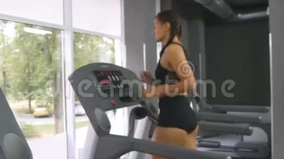 年轻强壮的女人有着完美的健身身材穿着运动服在健身房跑步机上跑步女子有氧运动视频的预览图
