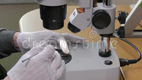 专业技术人员用烙铁修补显微镜工作台上的小型计算机部件特写镜头视频的预览图