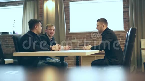 年轻的商人坐在一张桌子旁交谈视频的预览图