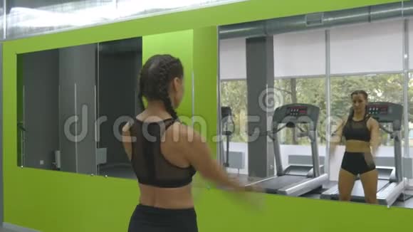 年轻的健身女子在健身房的镜子前训练女运动员在运动前伸展身体和双手视频的预览图