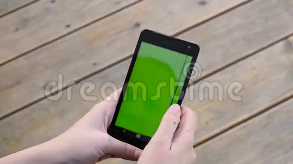 女人用手机用绿色钥匙屏幕木制视频的预览图